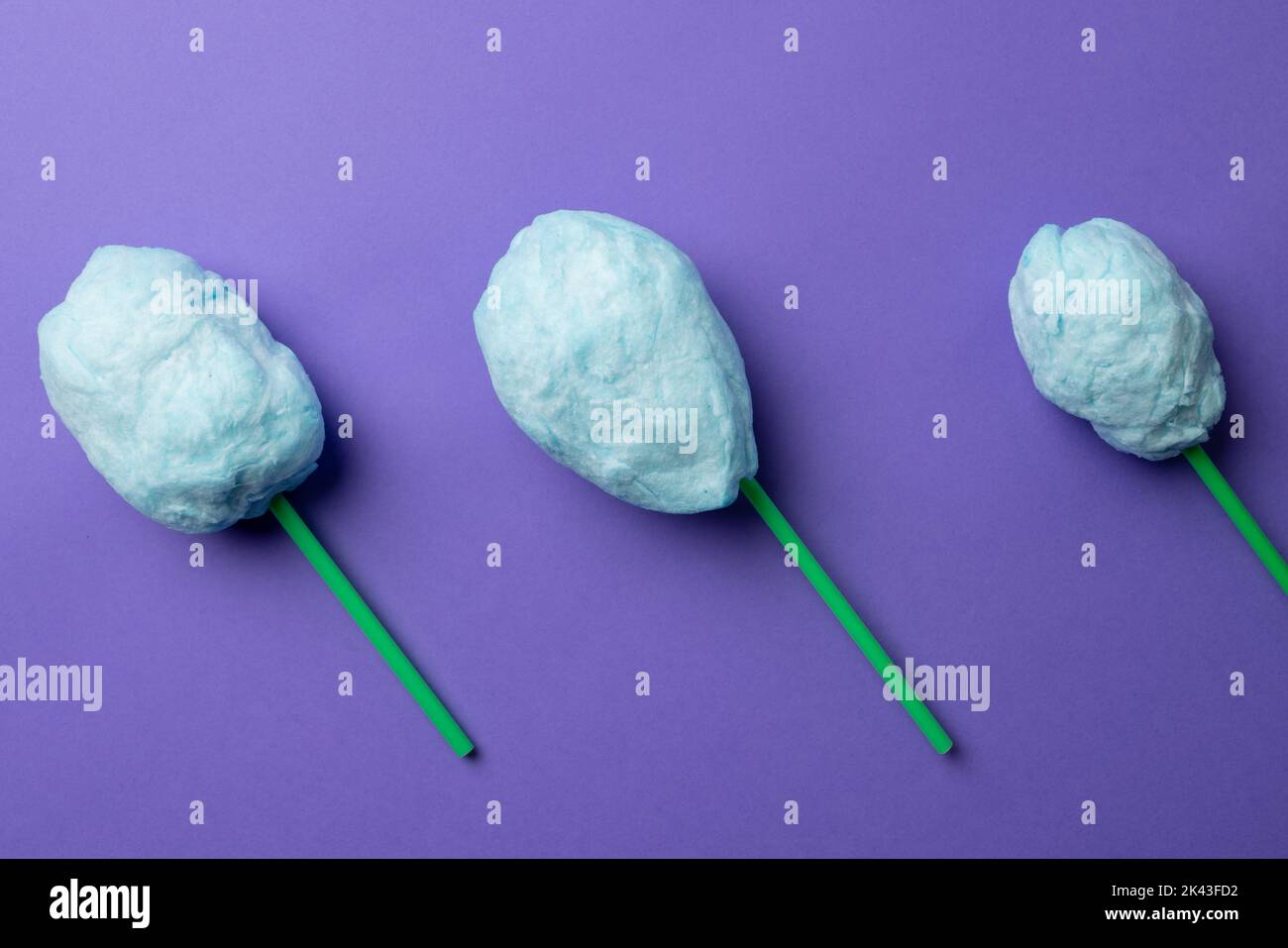 Horizontal image of homemade blue candy floss on three sticks, on