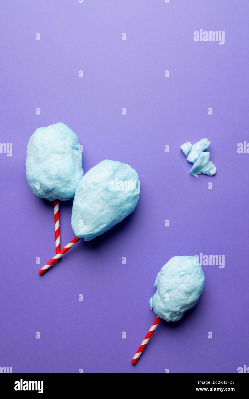 Vertical image of homemade blue candy floss on three striped sticks, on purple with copy space Stock Photo