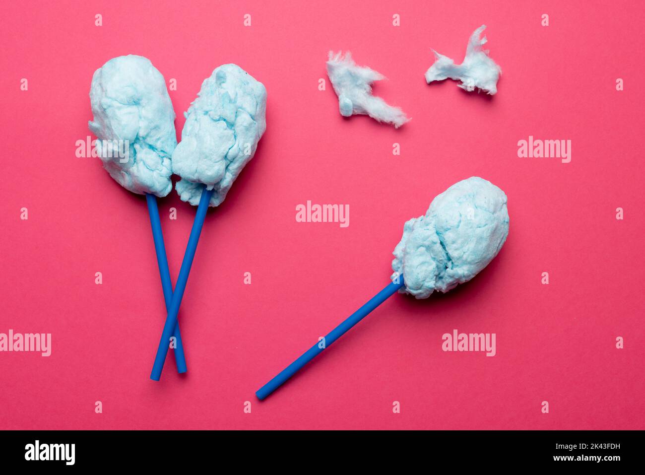 Horizontal image of homemade blue candy floss on three sticks, on pink background Stock Photo