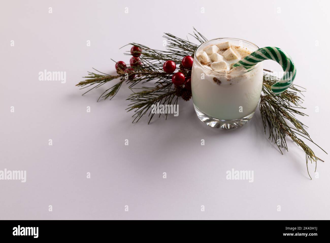 Image of glass of milk with marshmallows, candy cane, christmas decoration and copy space on white Stock Photo