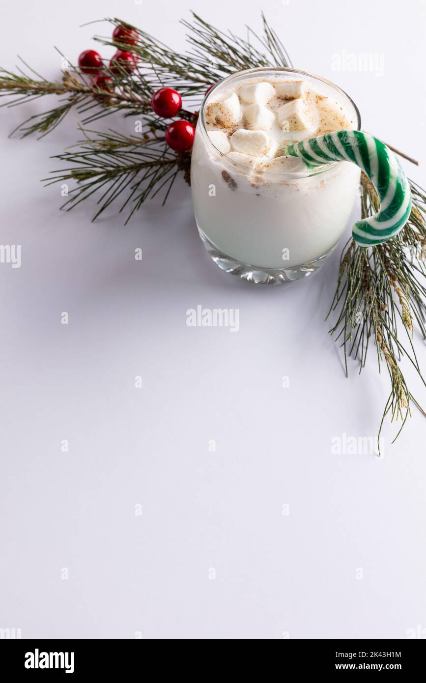 Image of glass of milk with marshmallows, candy cane, christmas decoration and copy space on white Stock Photo