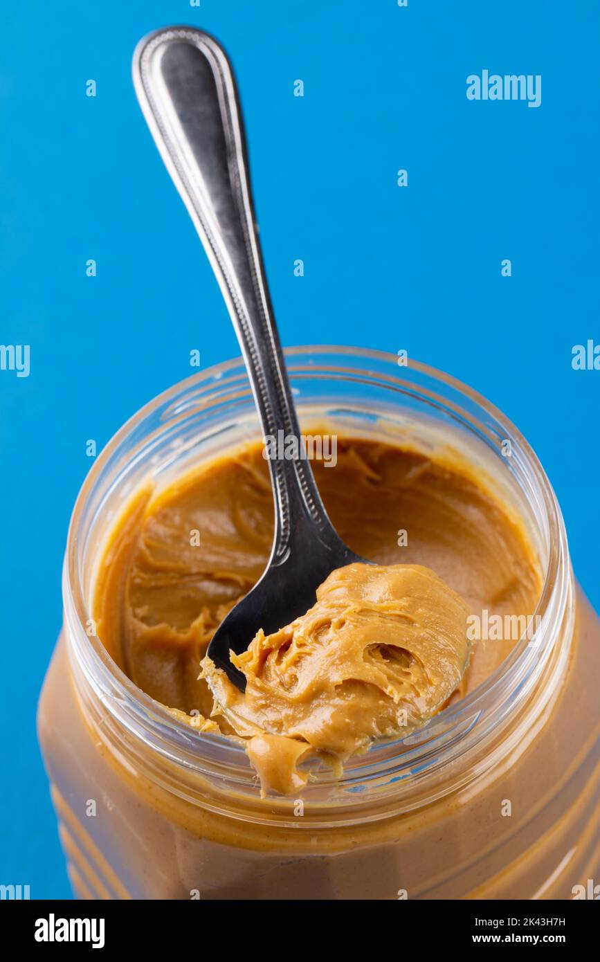 Vertical shot of the knife buttering the tasty peanut butter on the white  surface Stock Photo by wirestock