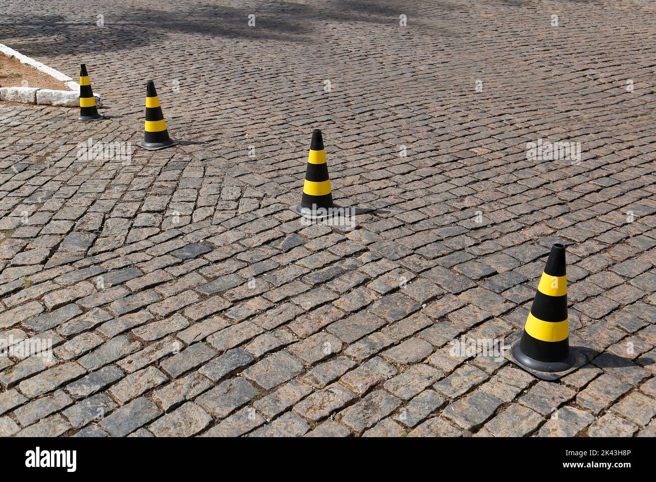 traffic signal cone yellow and black colors, hard plastic, on stone public road Stock Photo