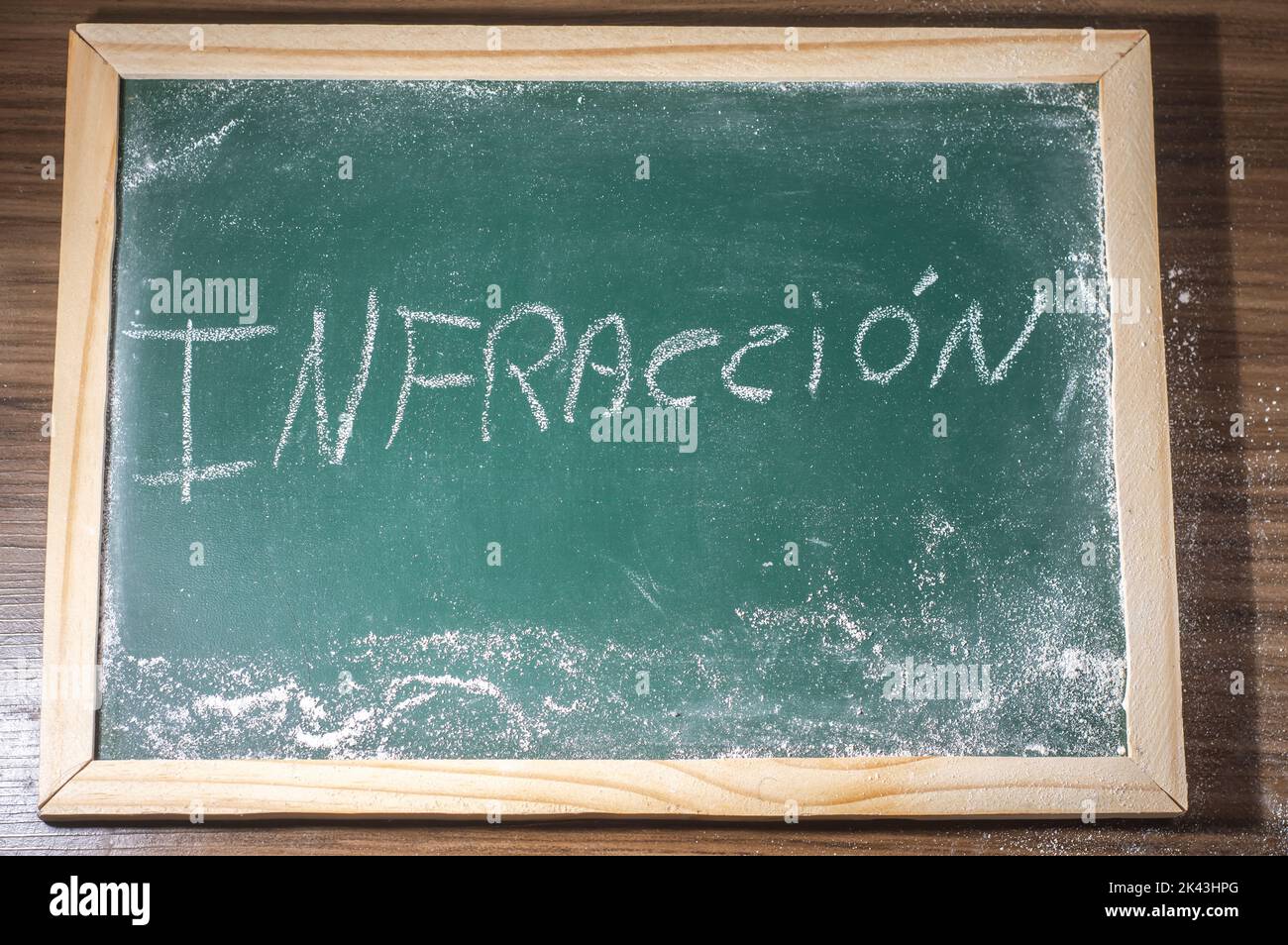 Green chalkboard with the word "infraction" written in Spanish with