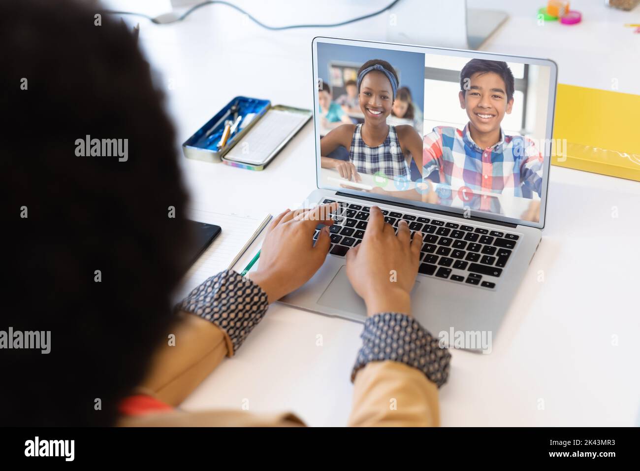 Mixed race female teacher using laptop on video call with school ...