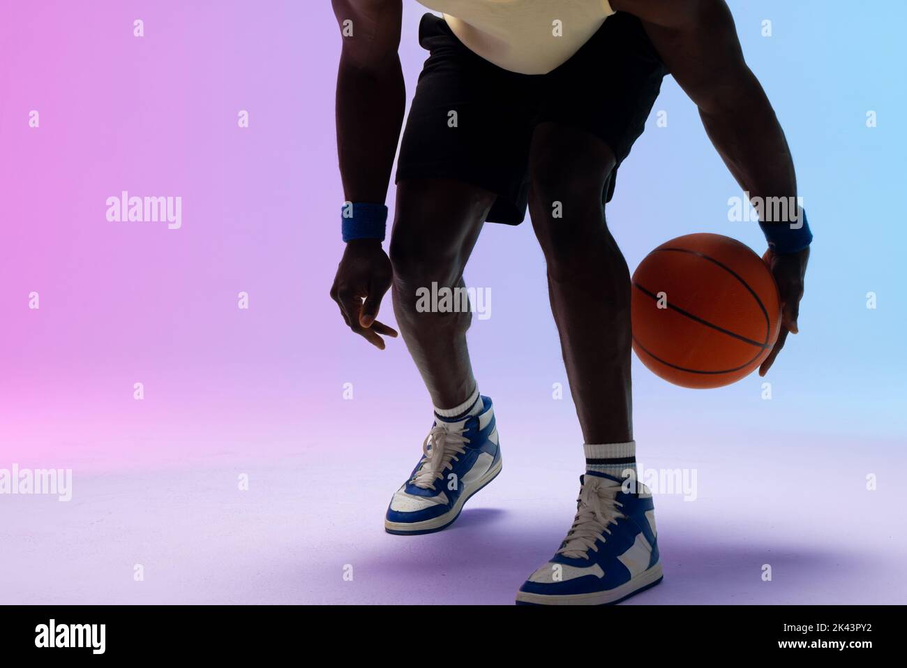 Image of african american basketball player with basketball on neon purple to blue background. Sports and competition concept. Stock Photo