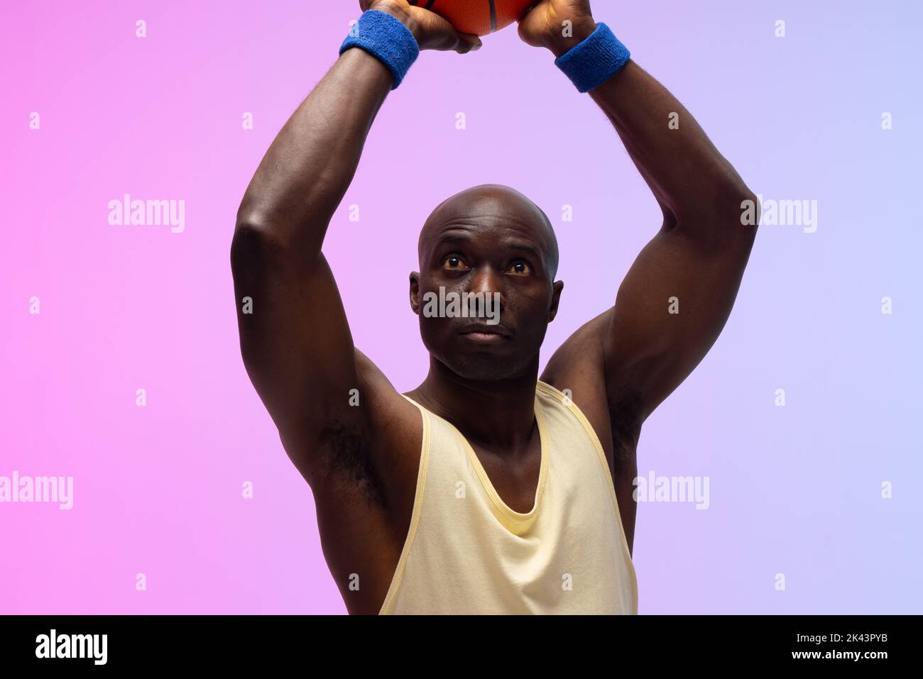 Image of african american basketball player with basketball on neon purple to pink background. Sports and competition concept. Stock Photo
