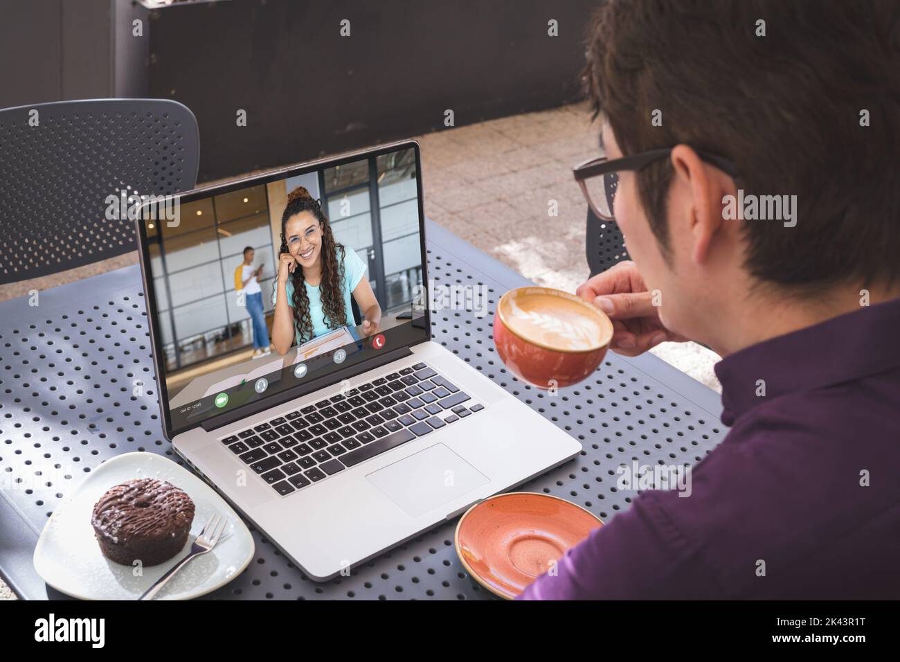 Multiracial businessman discussing with coworker on videocall over laptop while drinking coffee Stock Photo