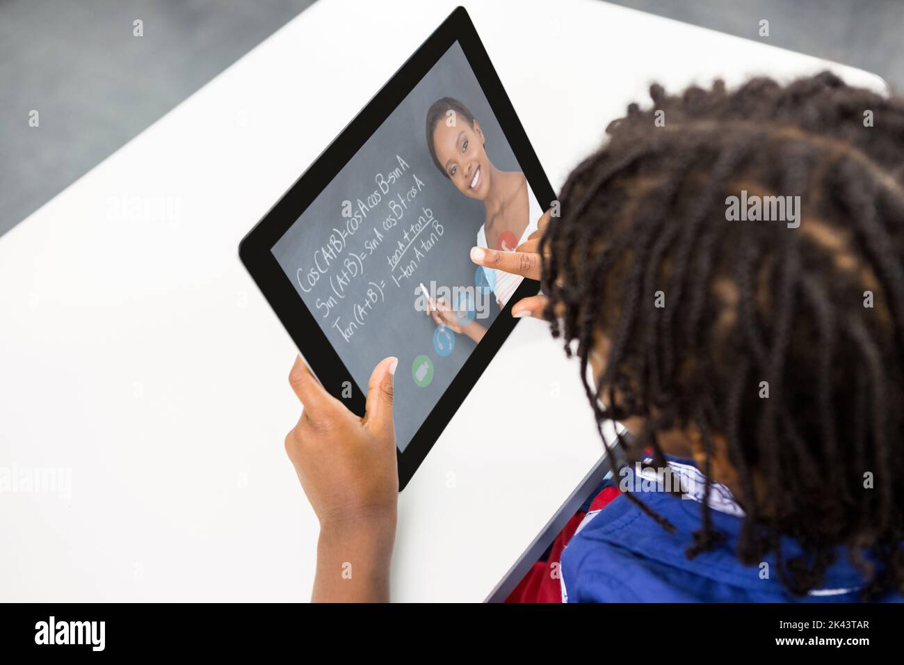 Male student having a video call with female teacher on digital tablet ...
