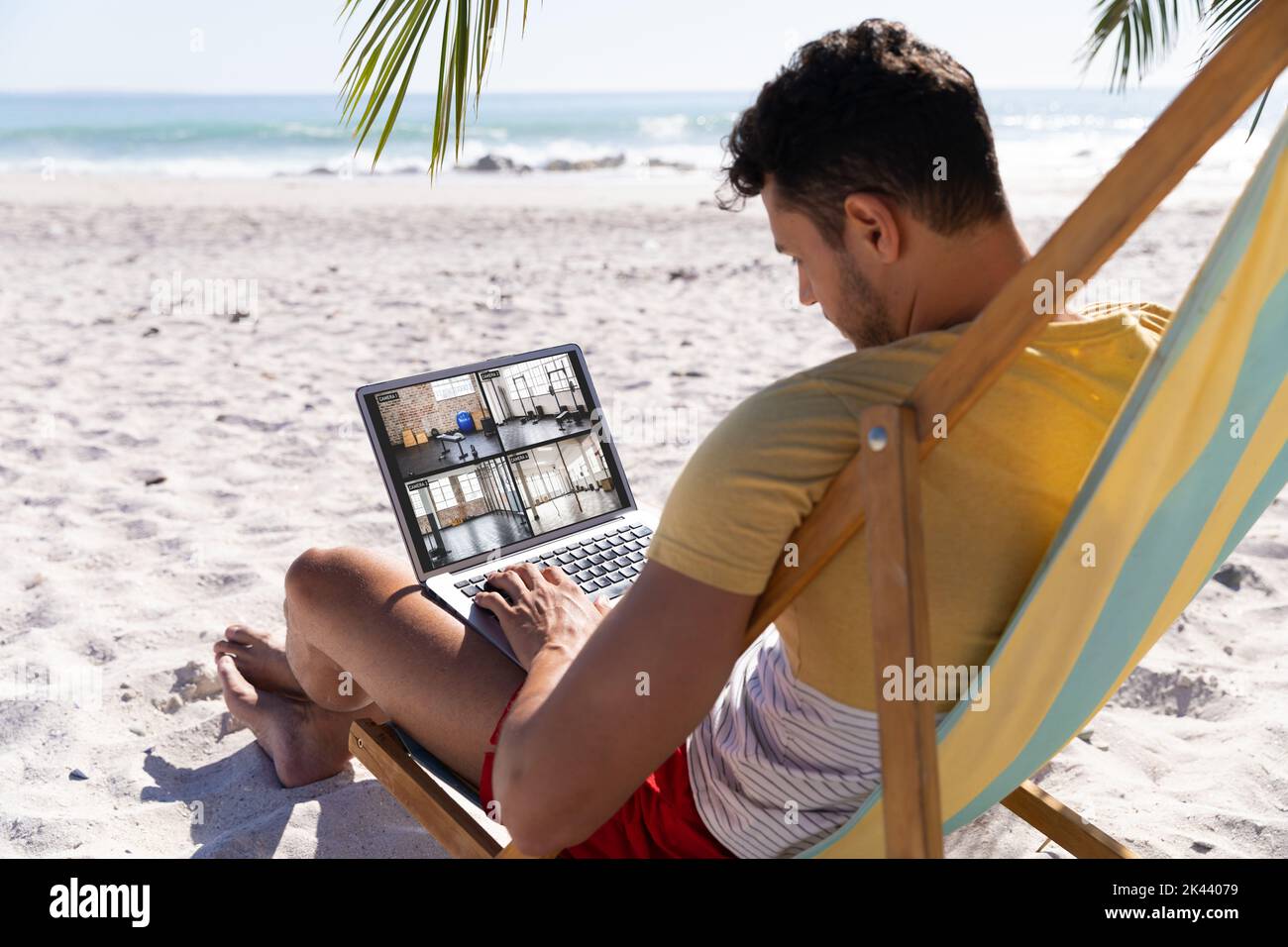 Caucasian man on holiday using laptop with view of gym from security