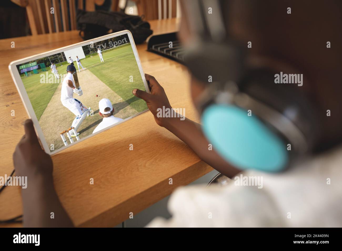 African american boy wearing headphones at home watching baseball game on tablet. sports, competition, entertainment and technology concept digital co Stock Photo