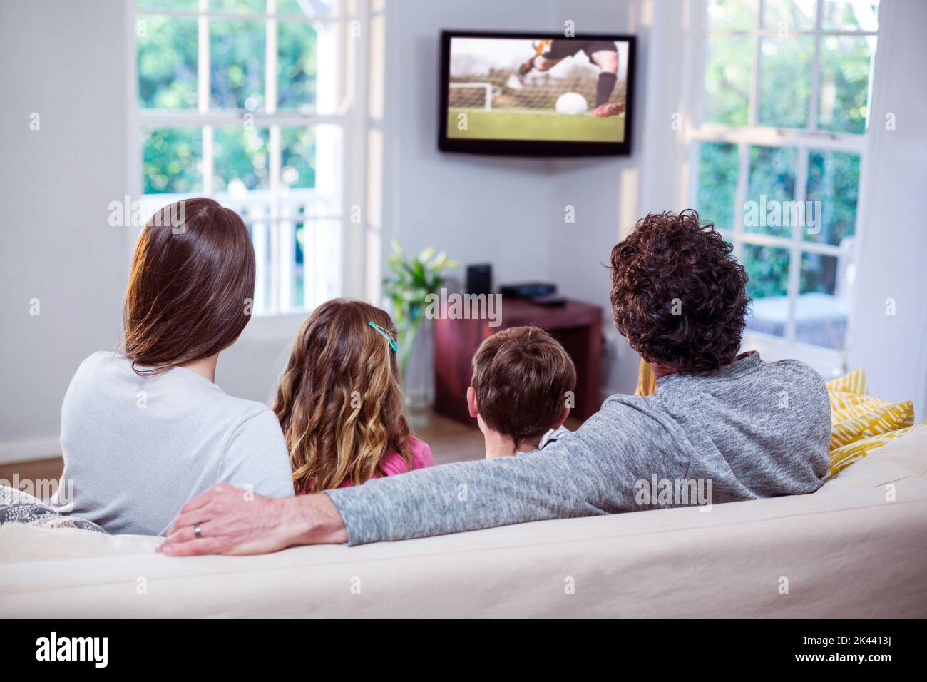 Family watching television while sitting on sofa at home Stock Photo