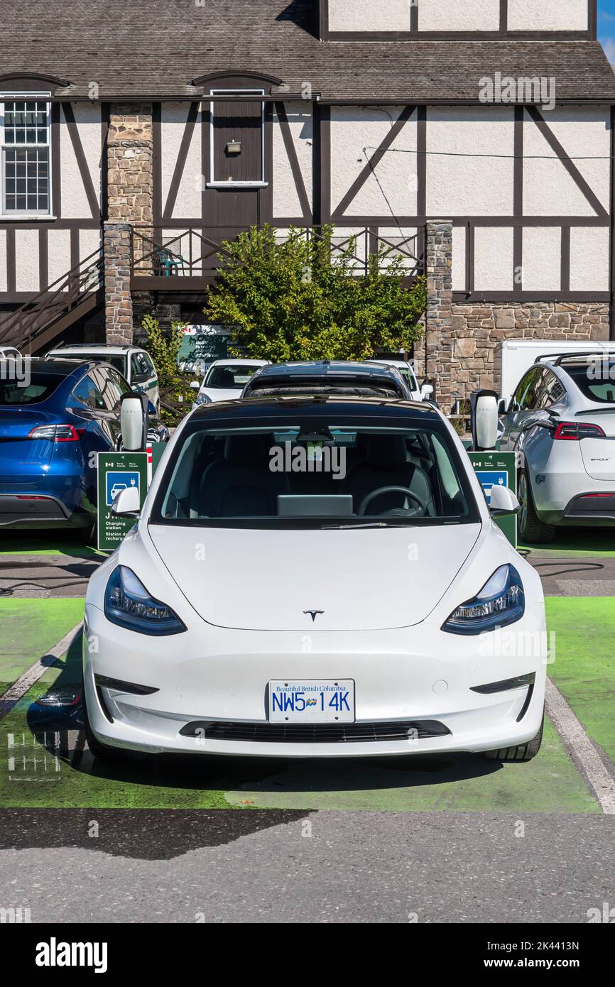 A white Tesla parked at a charging station in a parking lot in Banff