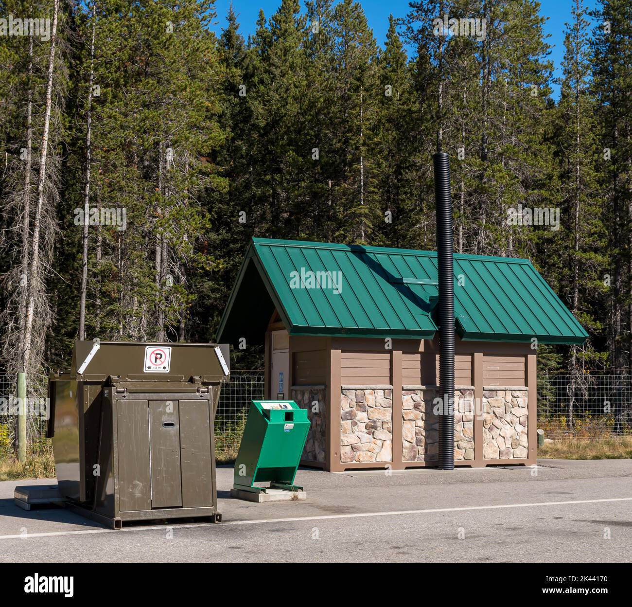 An animal proof garbage dumpster and a public bathroom facility at a rest stop in Field, British Columbia, Canada on a sunny day Stock Photo