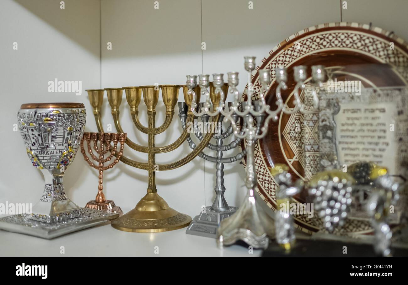 A Kiddush cup with golden hanukkah menorah and Hanukkiah on the shelf. Symbols of Judaism used as tradition for celebrating Jewish festivals. Nobody, Stock Photo