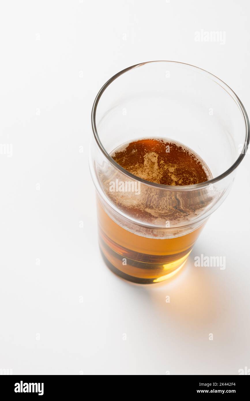 Overhead image of half full pint glass of lager beer, with copy space