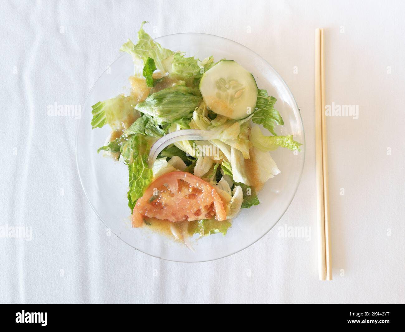Japanese salad with tomato, iceberg lettuce,cucumber and onion, served in plate with chopsticks Stock Photo