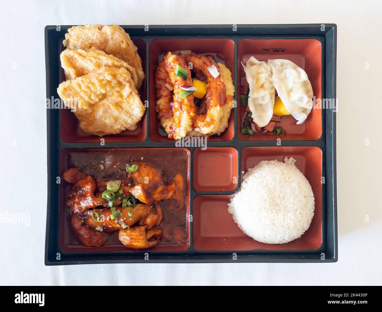 Traditional Japanese spicy chicken bento box with tempura vegetables, dumpling, onion rings and steam rice Stock Photo