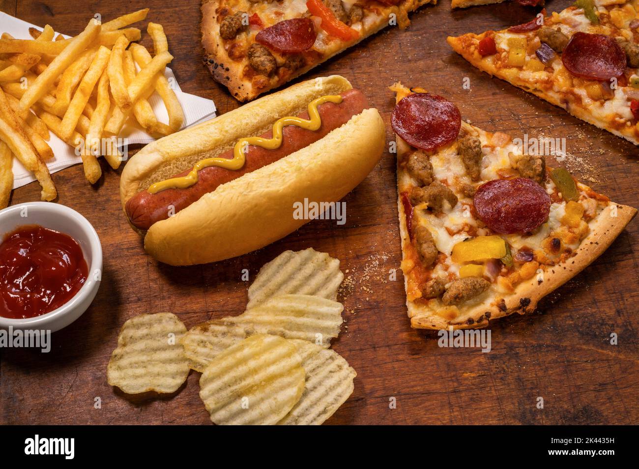 Variety of processed foods with pizza, hot dog, chips, and french fries Stock Photo