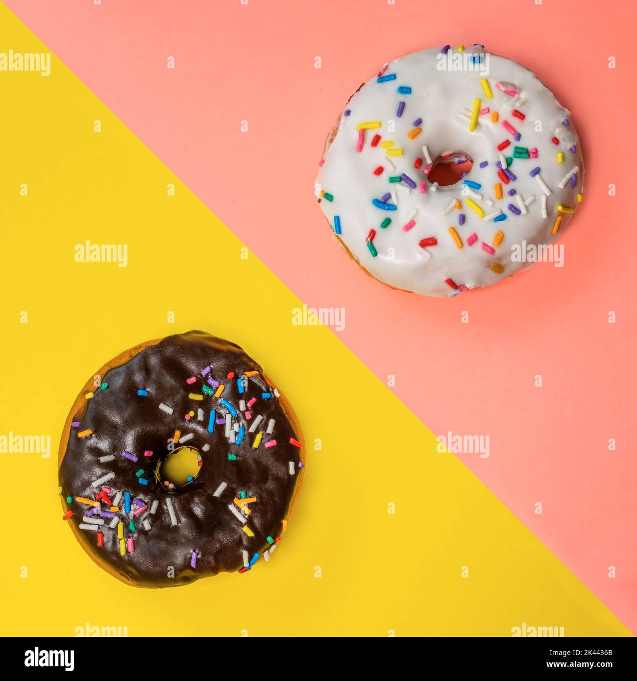 Overhead view of two donuts with icing and sprinkles on multi-colored background Stock Photo