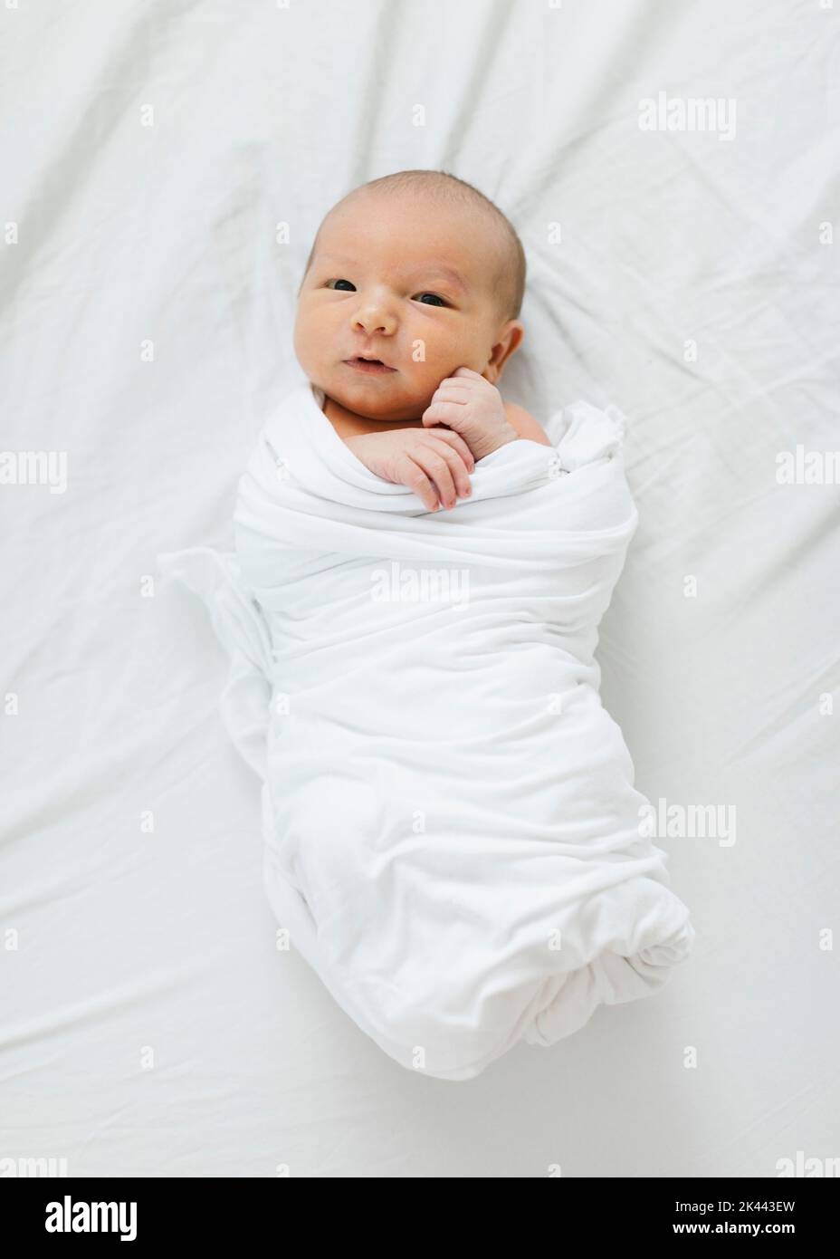 Overhead view of baby boy (25 months) in swaddle lying on bed Stock