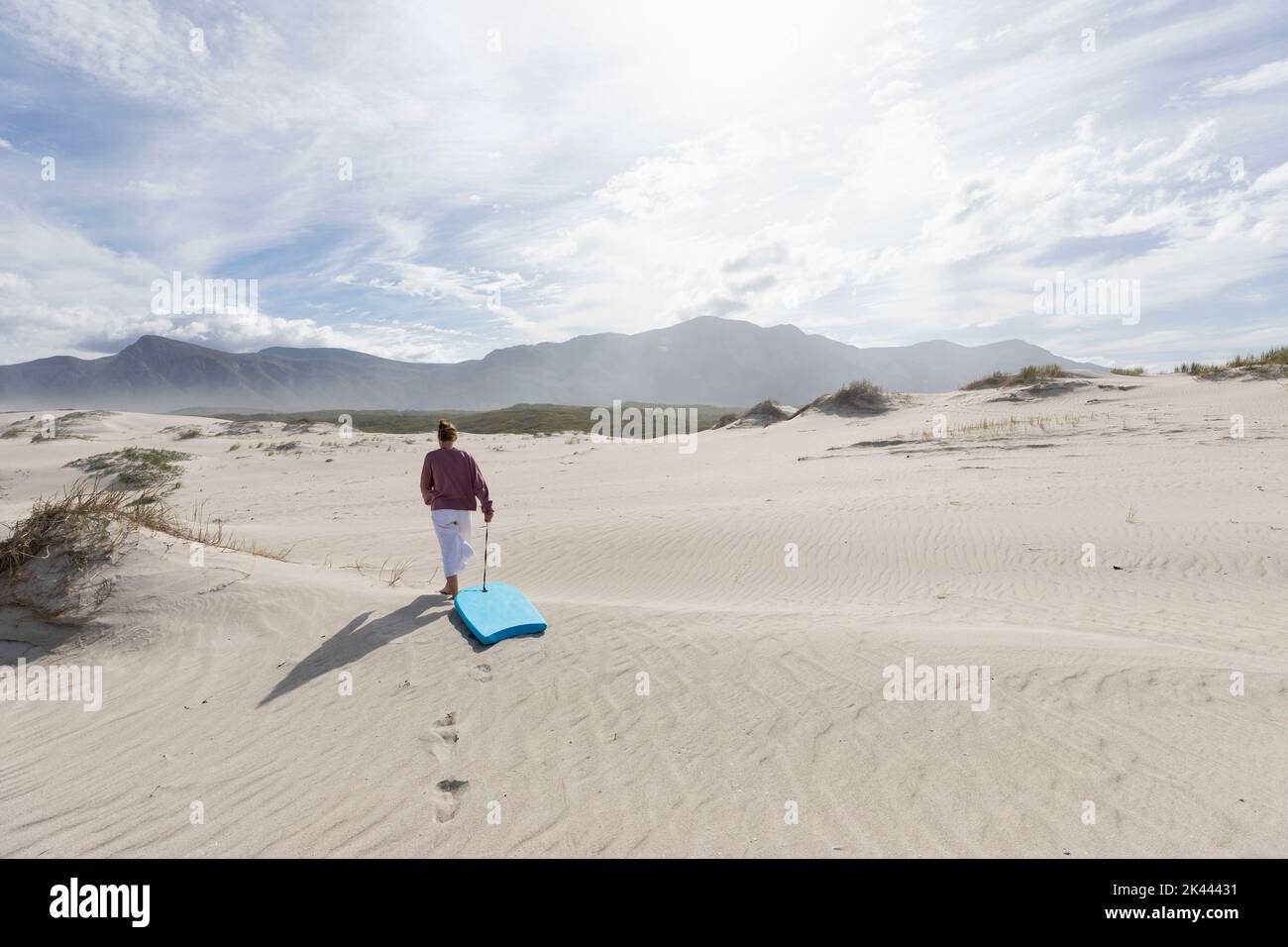 South Africa, Hermanus, Teenage girl (16-17) with body board on sand ...