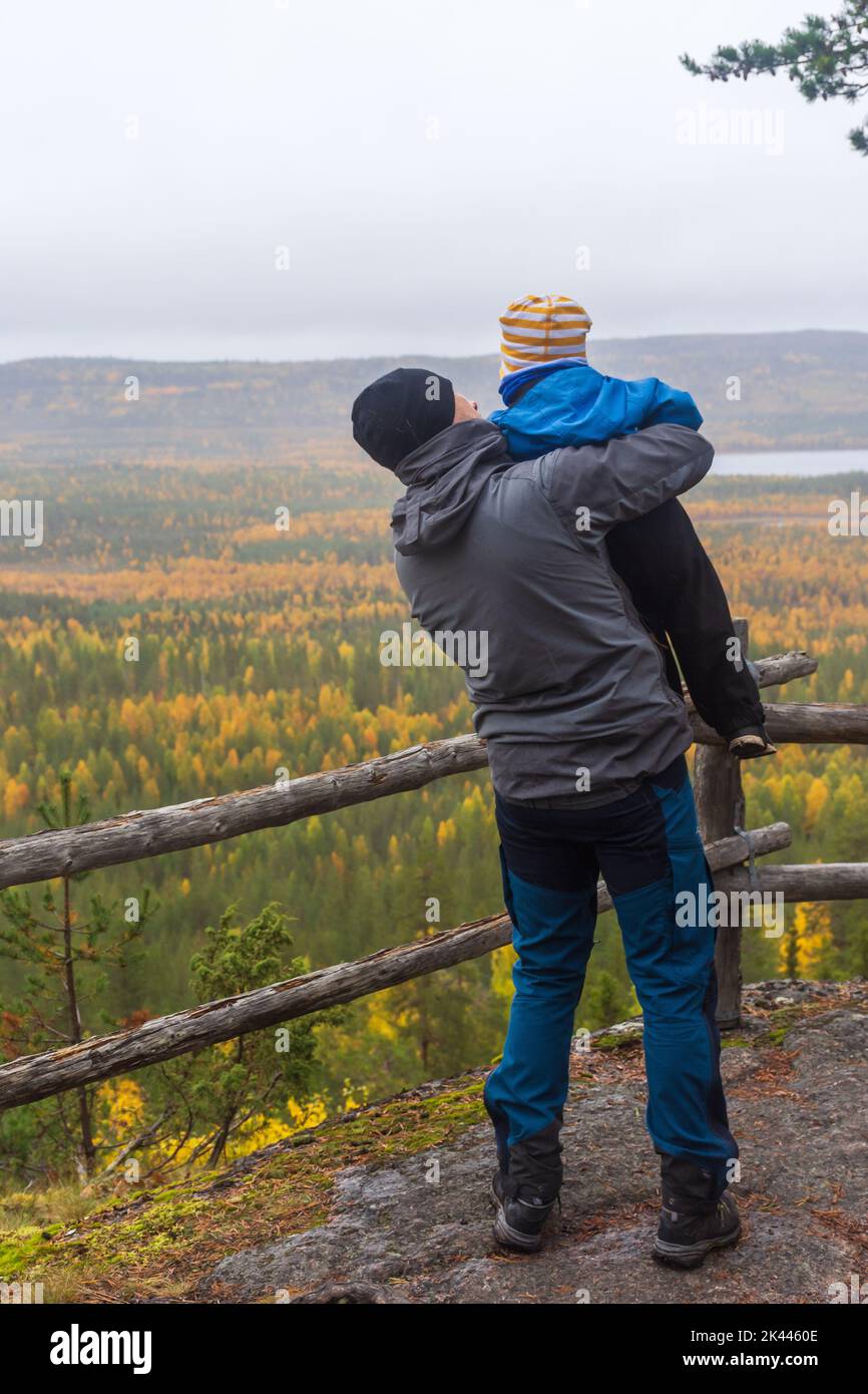 Man showing his child the drizzly autumnal landscape on top of Pallistajavaara dfell in Pello Finland Stock Photo