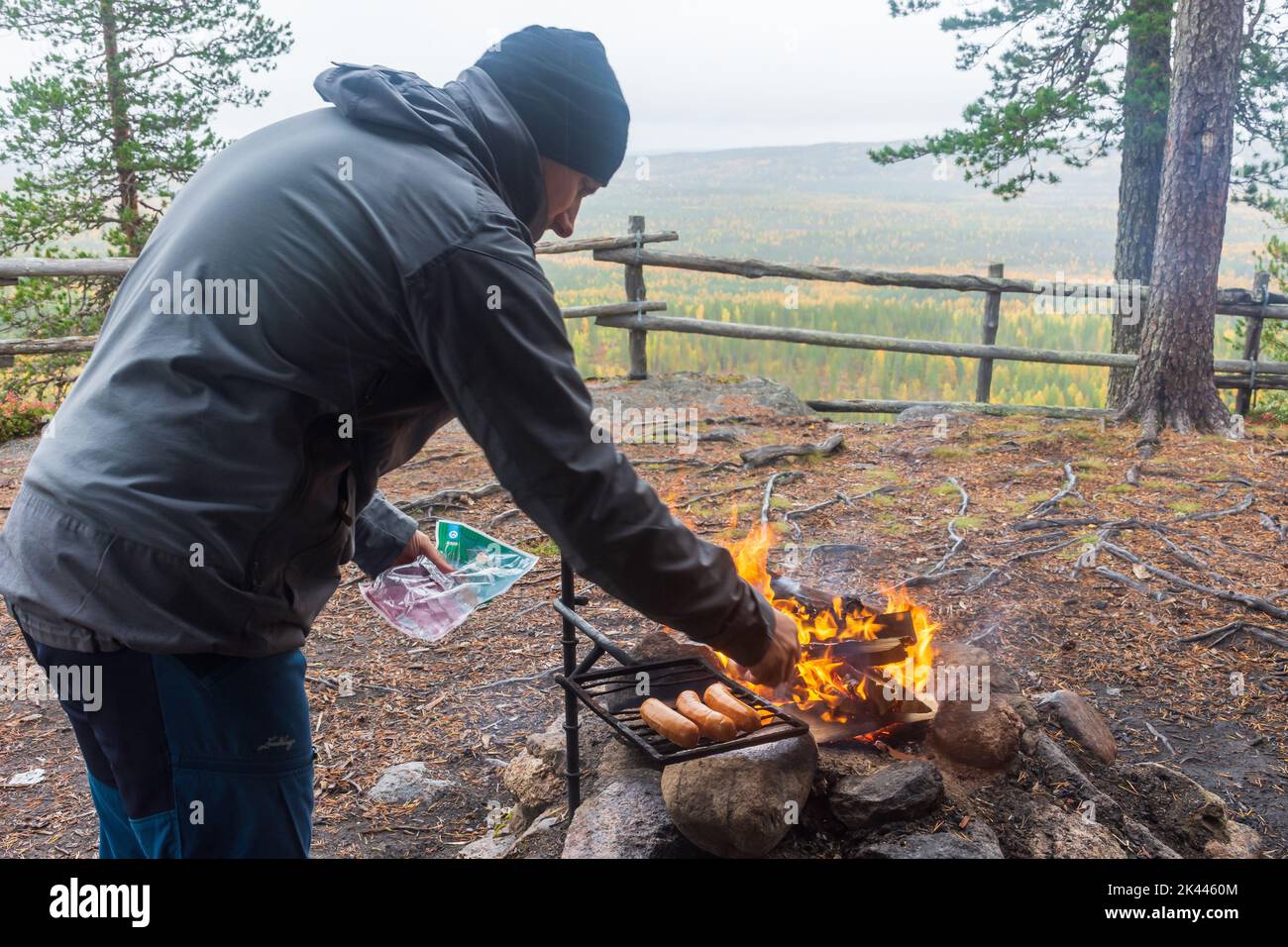 Man setting sausages over the fire to fry ant Pallistajavaara fell in Pello Finland Stock Photo