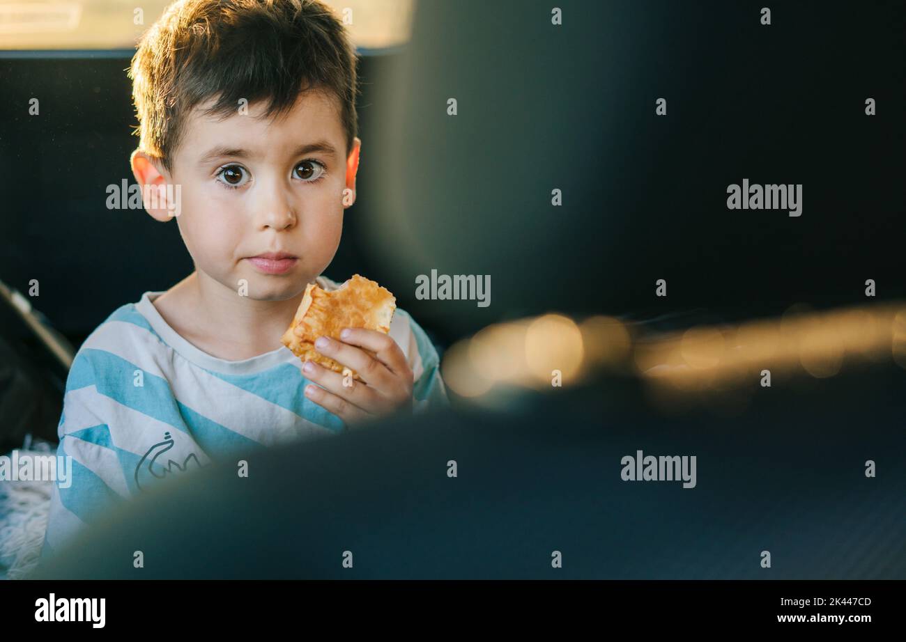 Boy looking innocently at the camera while sitting on the back seat of