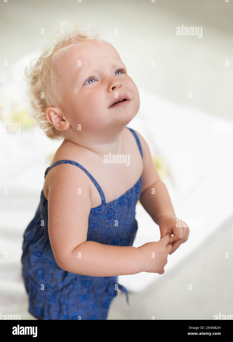 Separation anxiety. An unhappy baby girl looking up with tears in her eyes. Stock Photo