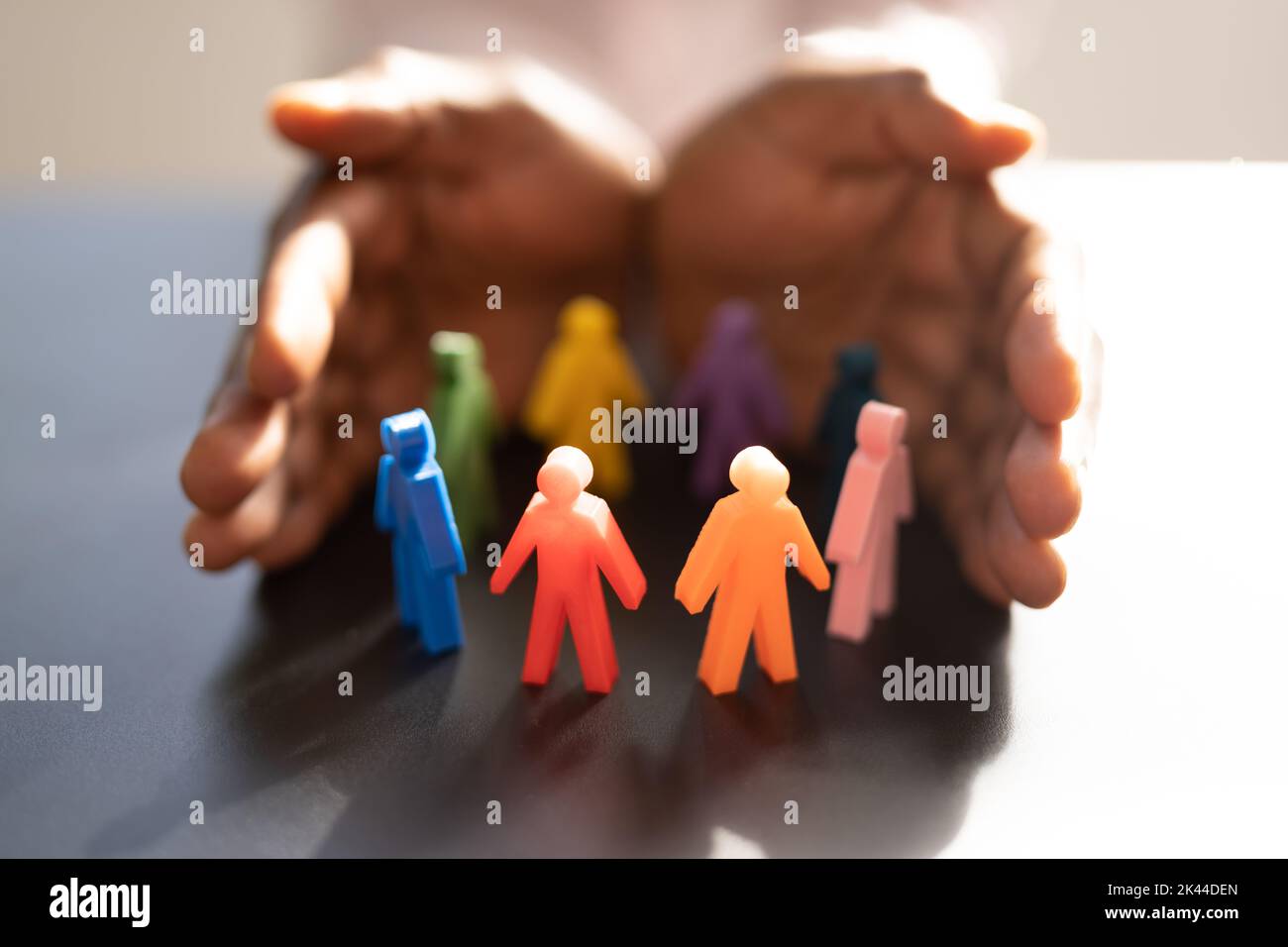 Inclusion And Diversity. Hand Protecting Inclusive Equal Pawns Stock Photo