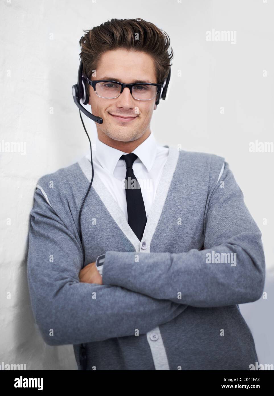 Confident support assistant. A young technical support engineer leaning against a wall. Stock Photo