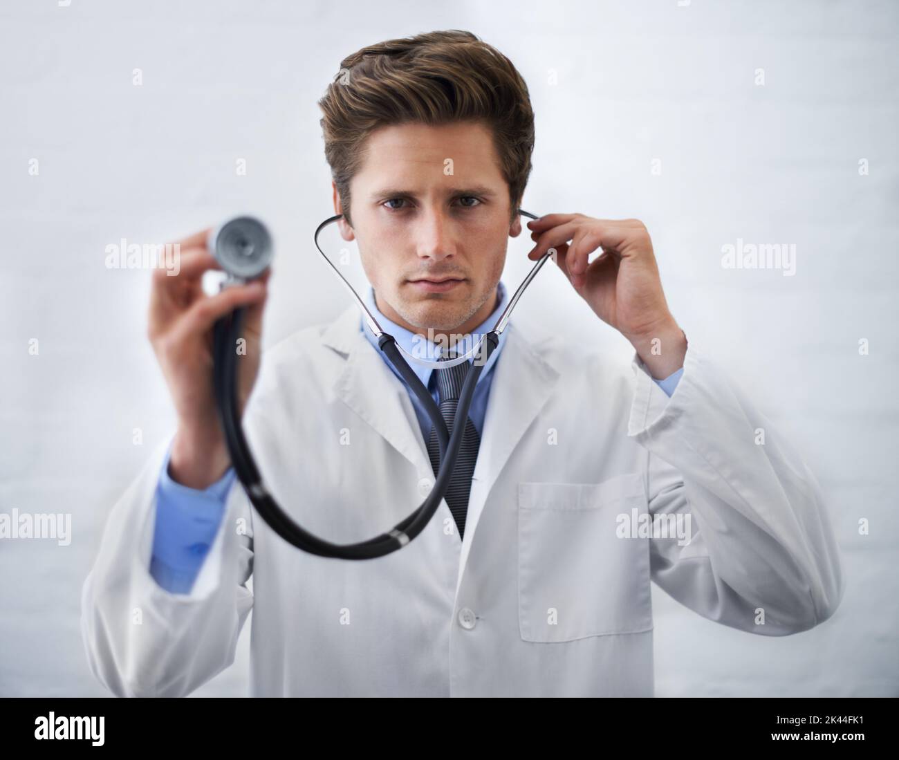 Examination time. a serious-looking doctor holding up the end of a stethoscope toward the camera. Stock Photo