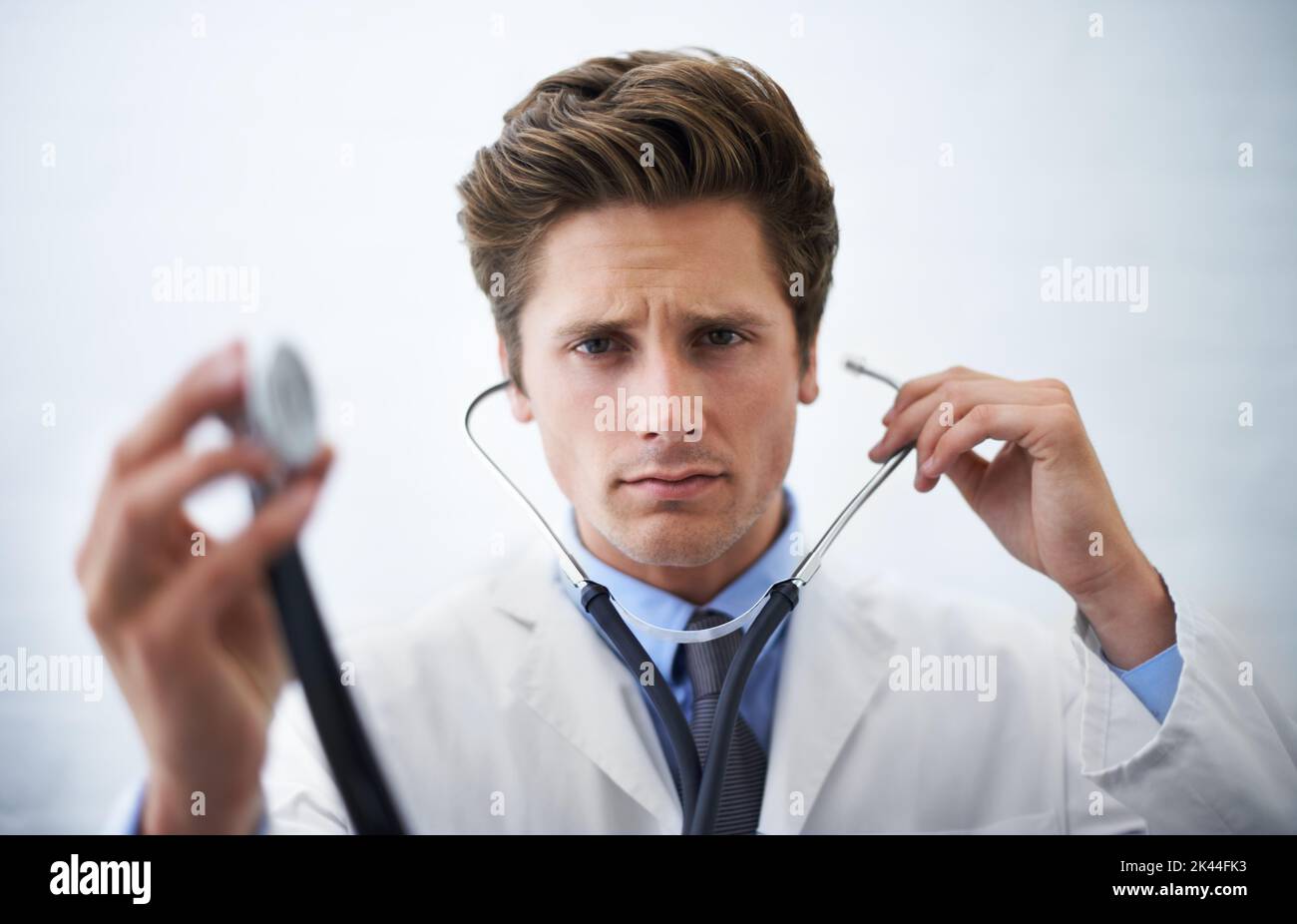 There may be an irregularity...a serious-looking doctor holding up the end of a stethoscope toward the camera. Stock Photo
