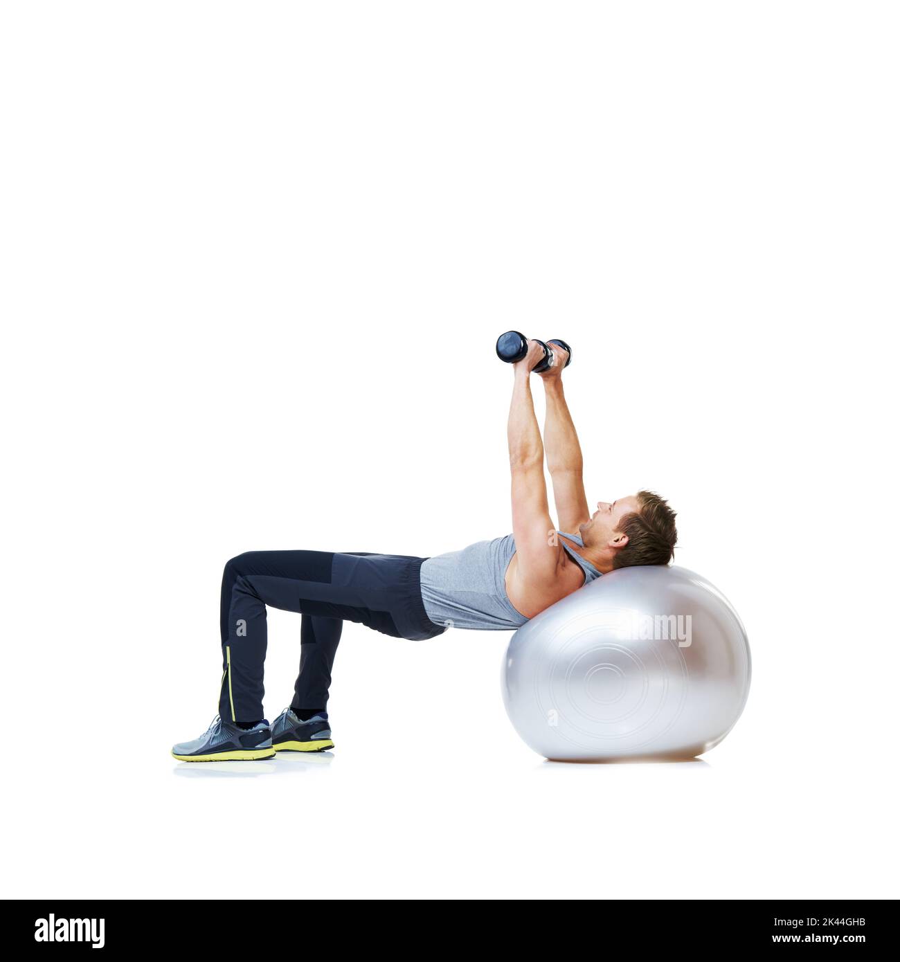 Working on his biceps. a man balancing on an exercise ball lifting