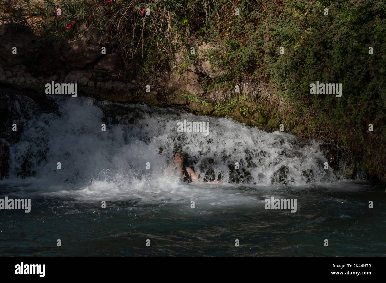 An Israeli woman bathes in a natural spring water pool of Amal stream which crosses Gan HaShlosha National Park also known by its Arabic name Sakhne in Israel Stock Photo