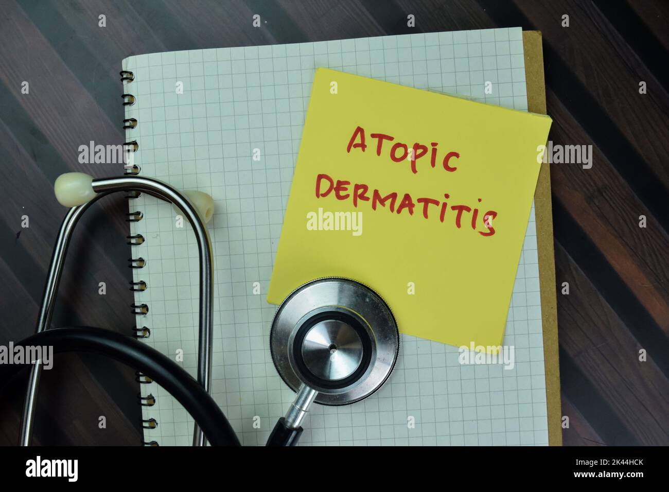 Concept of Atopic Dermatitis write on sticky notes with stethoscope isolated on Wooden Table. Stock Photo