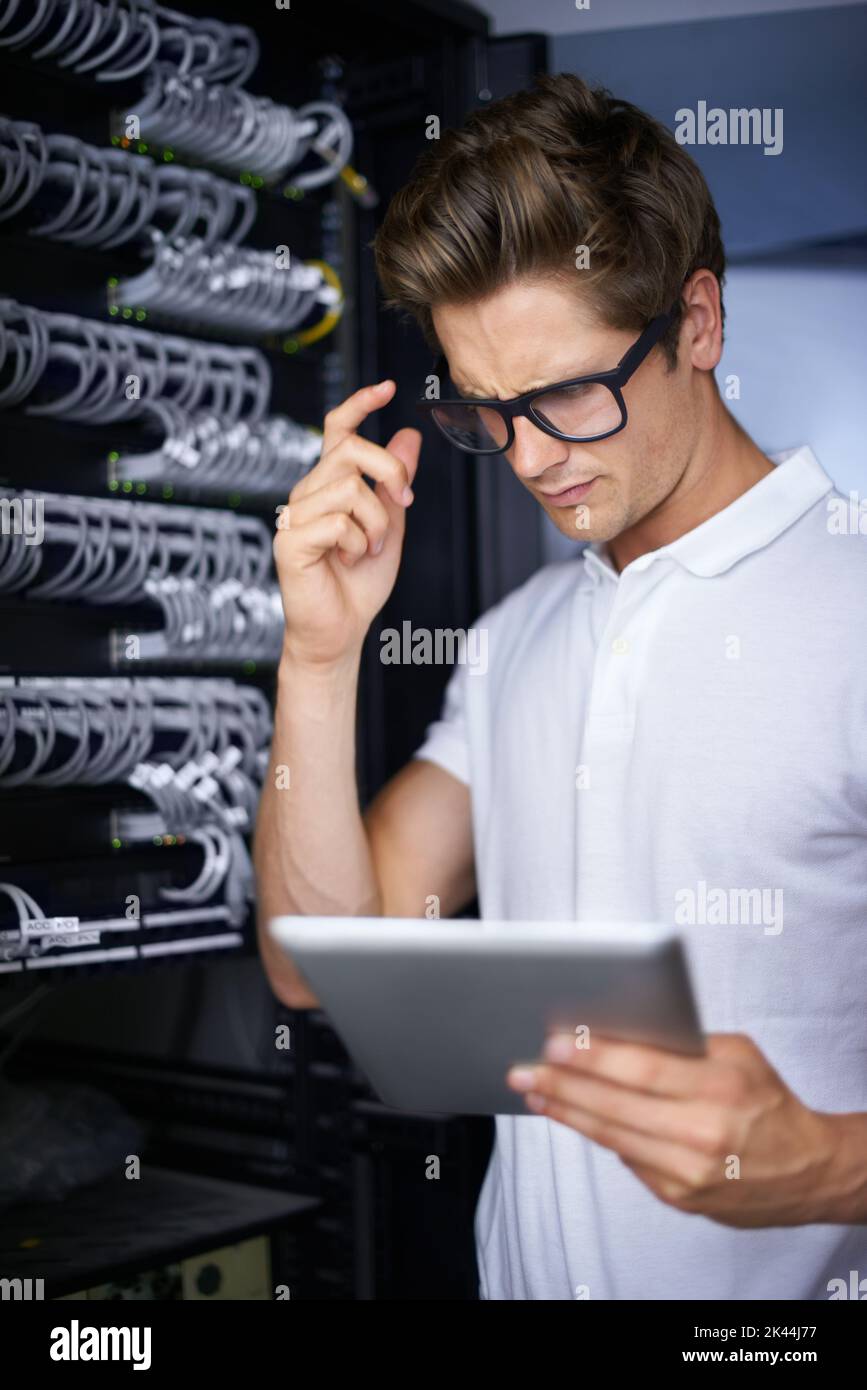 Taking care of your network needs. A confused technician looking at his digital tablet. Stock Photo