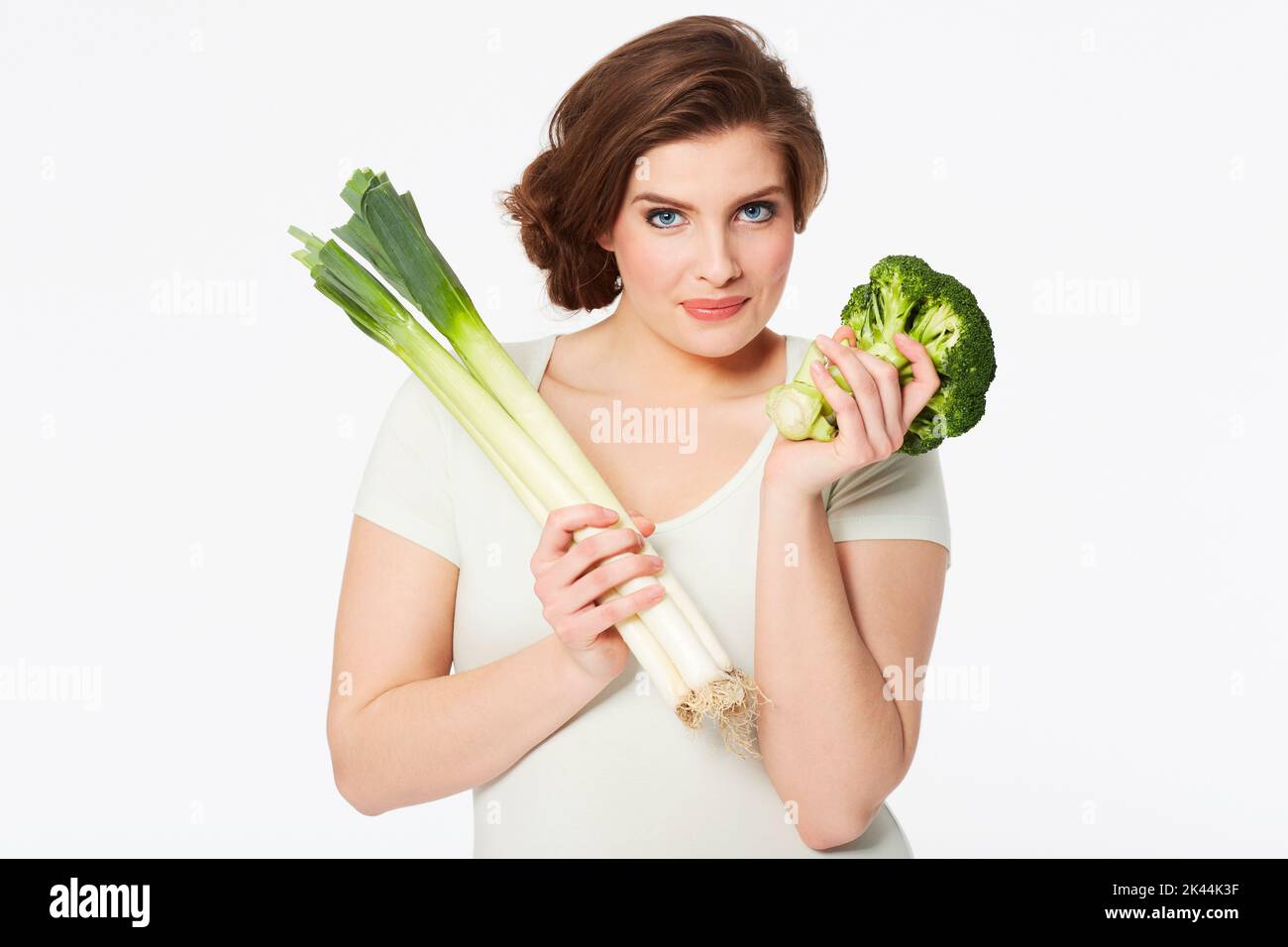 Healthy habit are important. Pretty brunette woman holding some healthy veggies while Isolated on white. Stock Photo