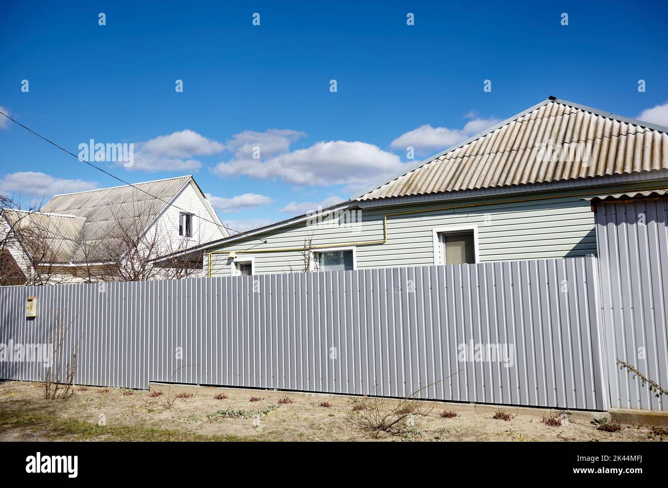 Facade of a European suburban building. Metal fence and house against a blue sky Stock Photo