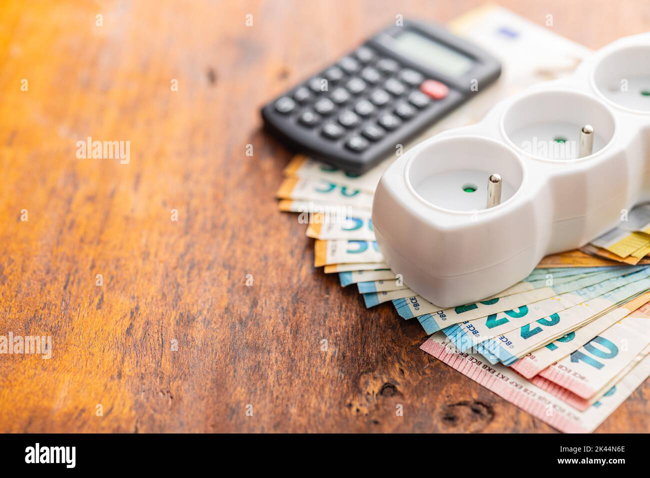 Electric socket and the euro money on the wooden table. Concept of increasing electric prices. Stock Photo