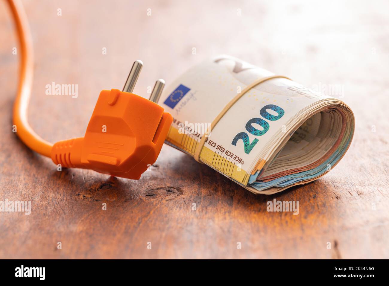 Electric plug and the euro money on wooden table. Concept of increasing electric prices. Stock Photo