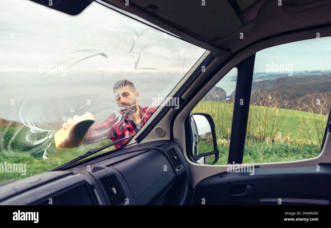 Man cleaning camper van windshield outdoor Stock Photo