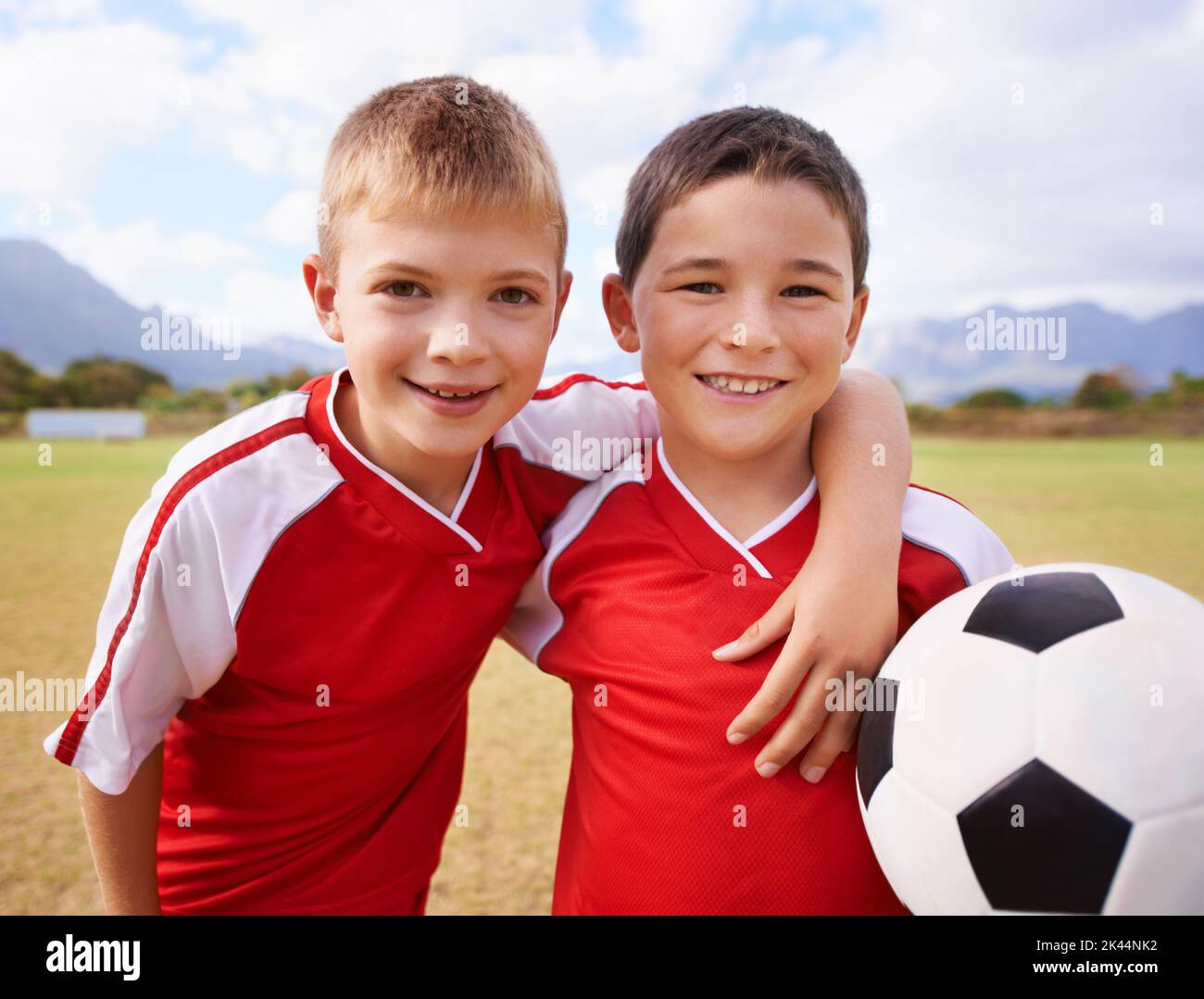 Team mates and best friends. Portrait of 2 boys smiling and holding a soccer ball. Stock Photo