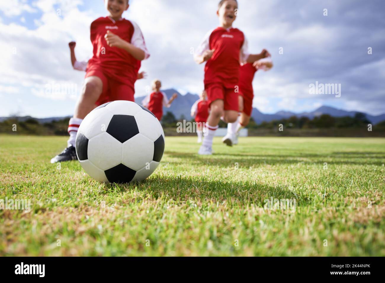 Learning teamwork while playing together. Low angle of kids playing soccer on a field Stock