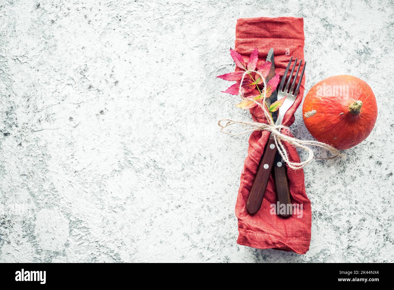 Thanksgiving autumn place setting with cutlery and arrangement of fall leaves on grey background. Thanksgiving holidays dinner concept. Mockup for sea Stock Photo