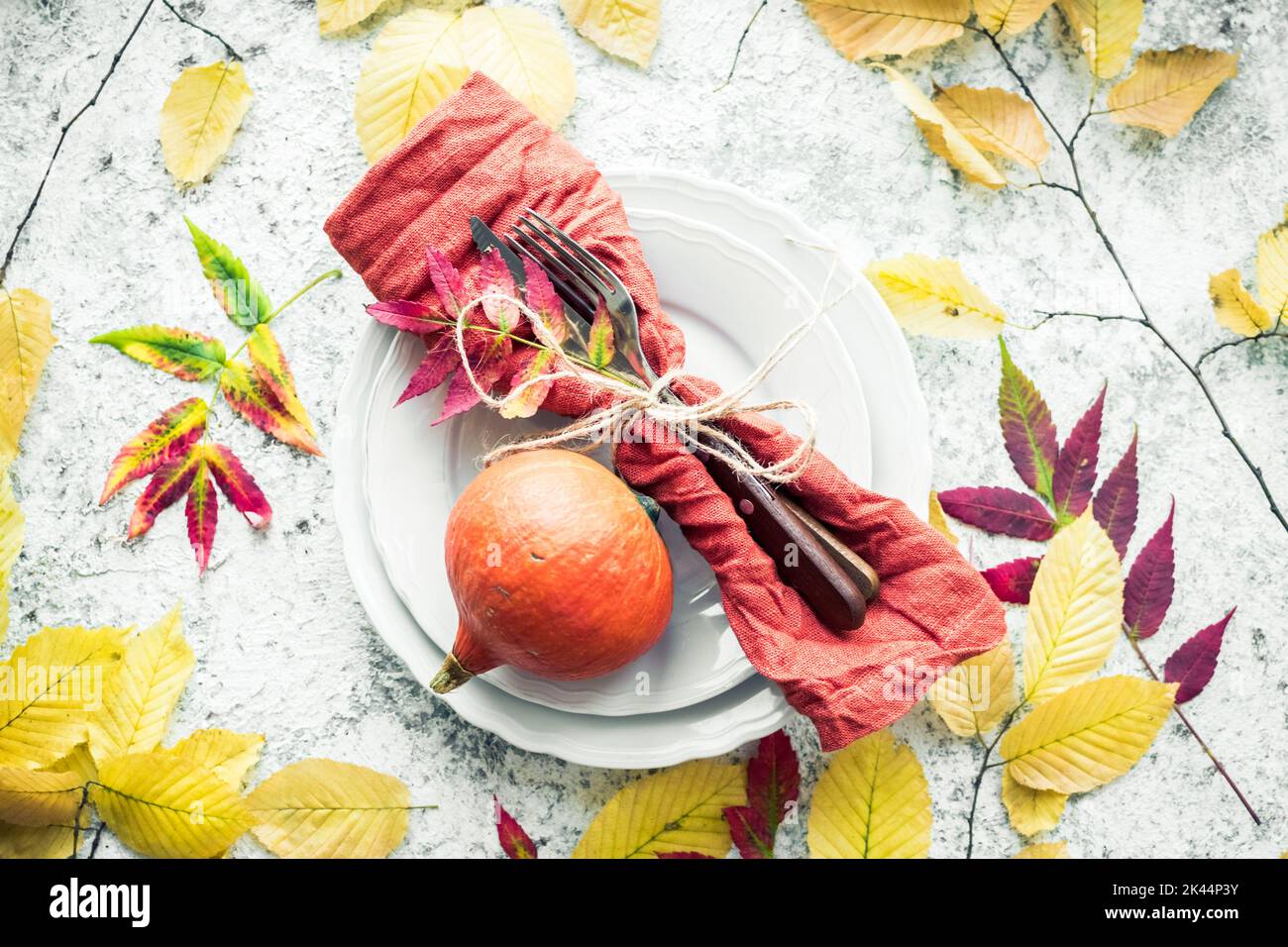 Thanksgiving autumn place setting with cutlery and arrangement of fall leaves on grey background. Thanksgiving holidays background concept. Top view. Stock Photo