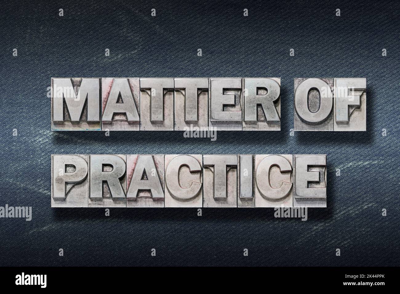 matter of practice phrase made from metallic letterpress on dark jeans background Stock Photo