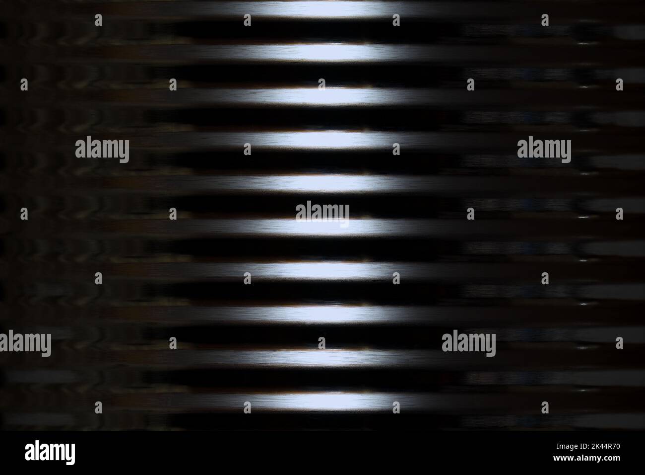 The outer side of a shiny round corrugated tin metal container with dark edges and a bright, vertical central highlight creating a cold, alien feel Stock Photo