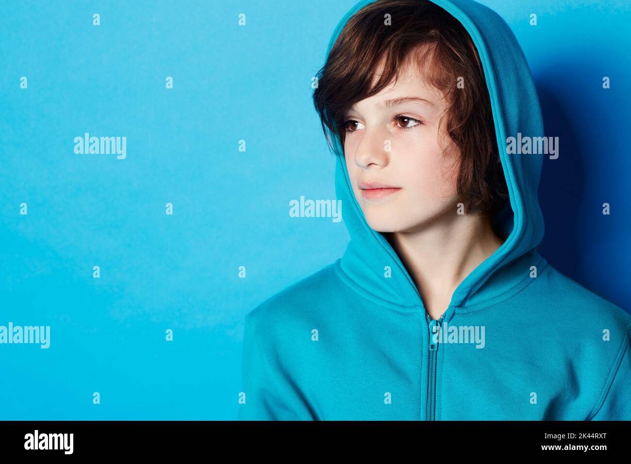 Casual contemplation. A young boy wearing a blue hoodie in the studio. Stock Photo